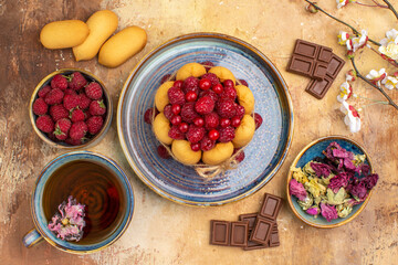 A cup of hot herbal tea soft cake with fruits chocolate bars on mixed color background