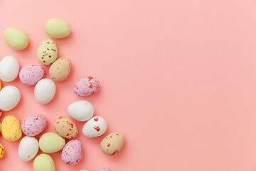 Happy Easter concept. Preparation for holiday. Easter candy chocolate eggs and jellybean sweets isolated on trendy pastel pink background. Simple minimalism flat lay top view copy space.
