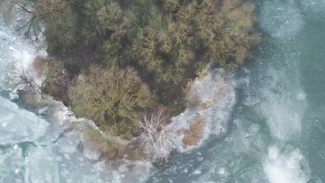 top view of an island in the middle of a frozen lake and fishermen catching fish