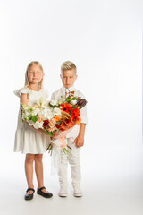 Studio portrait boy gives girl festive bouquet, congratulatory concept, white background, copy space