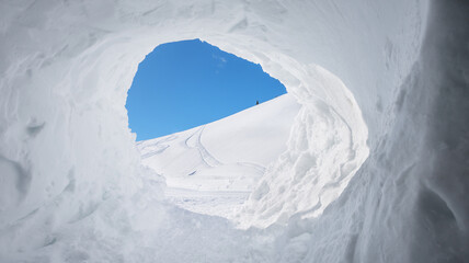 view out from snow cave into winter landscape and blue sky