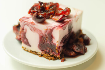 Japanese cheesecake with cherry sauce and fresh cherries on the ceramic plate and red background