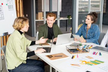 Fototapeta premium Happy young male mobile app developer looking at one of his female colleagues