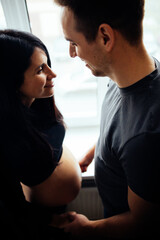 Affectionate pregnancy photo shoot at home. Spouses are waiting for the baby. 