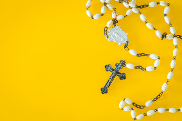 Christian rosary on a yellow background. Place for text