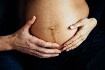 Close up photo shoot of pregnant bump with hands on it.