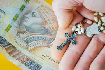 Christian rosary hand-held with money. Concept of church business and corolla. Polish two hundred...