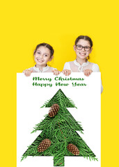 Happy little kids peeking from Christmas banner blank on yellow background. Kids holding banner blank with Christmas tree. Sale, holidays, christmas, new year, x-mas concept.