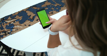 Woman s Hand is Holding Chroma Key Green Screen in vertical Position. Using Phone in Restaurant, Watching, Surfing, Scrolling