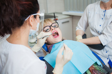 Closeup shot of dentist in protection mask working with tooth cavity and plague. Patient on...