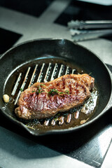 Appetizing roasted beef steak seasoned with aromatic herbs on grill frying pan