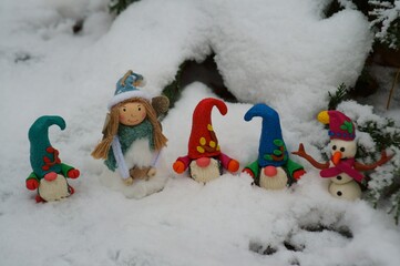 figures of colorful dwarfs in a snowy forest. Next to a snowman and a toy angel.