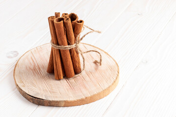 Bunch of cinnamon sticks tied with twine on white wooden table.