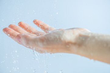 Fototapeta premium A woman's hand in the contour light with water drops of pure water. Moisturizing or skin care, clean and fresh.
