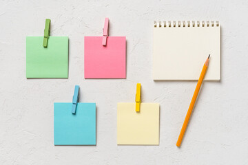 Four colorful blank post-it notes every with wooden clothespin and spring notepad with pensil on a...