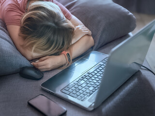 Girl in casual sleeping on the sofa with laptop and smartphone in front of her