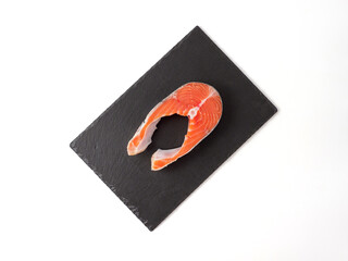 Salmon steak isolated on black cutting board.