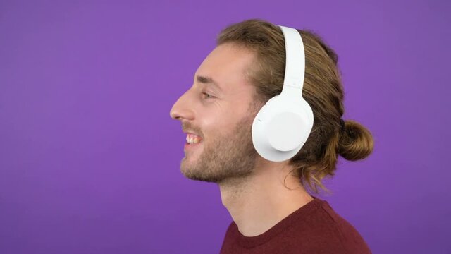 close-up portrait of a young man in big white headphones.Man .young man dancing head. Isolated on purple background. 4K