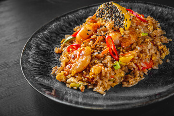 Fried rice with shrimp and vegetables in plate on wooden table background