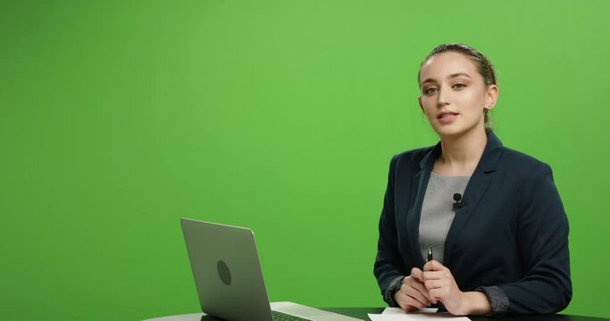 Professional female news anchor talking during live broadcast. Beautiful newscaster reporting on current events on green chroma key background 4k footage