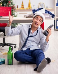 Young handsome employee celebrating Christmas at workplace