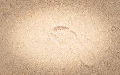 Trace d'empreinte de pied nu sur du sable de plage.