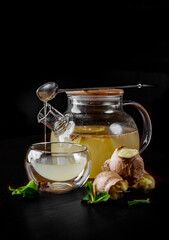 tea pot and Cup of ginger tea with honey and lemon on black background