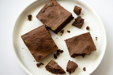 Chocolate brownie sliced into square slices on a white plate.