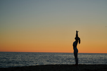 young spanish girl doing exercise in front of the mediterranean sea at sunset