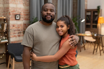 Happy African teenage girl embracing her father in home environment