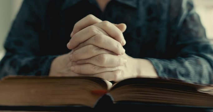 Praying hands over the bible