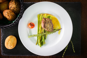 steak with aspasteak with asparagus served on a stone stand with buns and appliancesragus