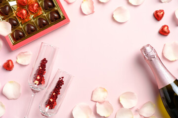 Happy Valentines Day concept. Champagne bottle, glasses, rose petals, sweets on pink table. Flat lay, top view. Romantic dinner