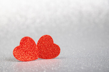 Fototapeta premium two red hearts in glitter on a silver glitter background