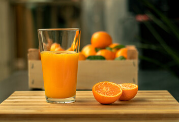 Orange juice with oranges beside it on a wood board