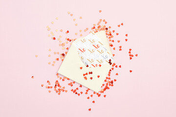Envelope with greeting card and red confetti on pink desk. Flat lay, top view. Valentines Day, Mothers Day, birthday greeting card.