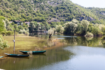 Naklejka premium Fishing boats moored on overflowed bank of the Rijeka Crnojevica town. It is near the coast of Skadar lake. The Balkan Peninsula, Montenegro