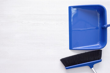 Broom and dustpan on the white wooden floor background with copy space.