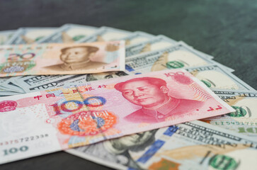 Chinese Yuan and USD dollar bank note, currency exchange rate. Black wooden background.