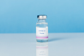 Vial with vaccine against COVID-19 and syringe on a blue background.
