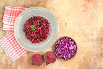 Fototapeta na wymiar top view red healthy salad dressed with parsley leaves made of beetroots and bowl of chopped cabbage on a wooden background with copy place