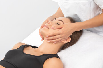 Masseur makes a relaxing massage on the face, neck, shoulders and collarbones of a young beautiful woman in a spa. Cosmetology and massage concept.