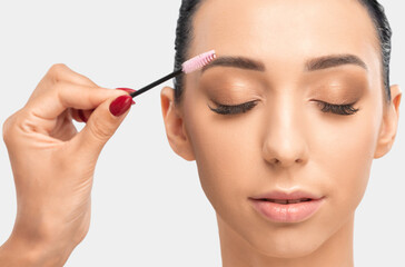 Fototapeta premium Makeup artist combs eyebrows with a brush after dyeing in a beauty salon.Professional makeup and cosmetology skin care.