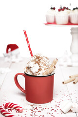 Delicious cocoa with whipped cream, cinnamon and marshmallows on white wooden background with Christmas decor.