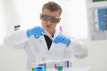 A male chemist holds test tube of glass in his hand overflows a liquid solution of potassium...