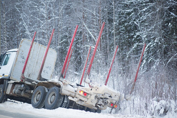 A logging truck on ice went into a ditch. Accident on the road in winter.