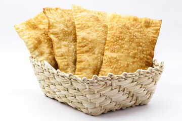 Brazilian pastry, traditional pastry called fried meat pastry, in straw basket, isolated on white...