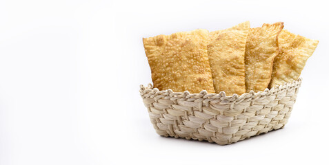 Brazilian pastry, traditional pastry called fried meat pastry, in straw basket, isolated on white...