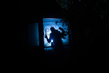 Silhouette of an unknown shadow figure on a door through a closed glass door. The silhouette of a human in front of a window at night.