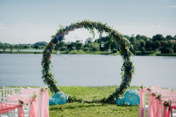 Obraz na płótnie Canvas wedding arch on a large green lawn overlooking the lake